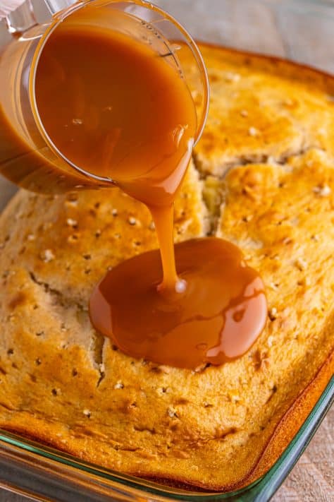 Caramel sauce being poured on a cake.