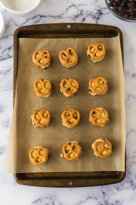 pretzels with cookie dough in between them and layered on a baking sheet.