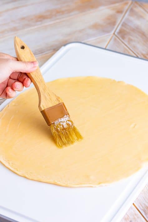 Melting butter being brushed on a pie crust.