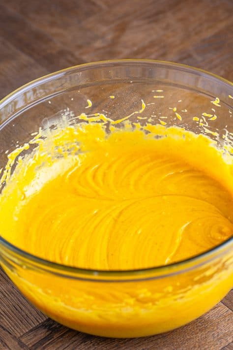 A mixing bowl with A mixing bowl with cake mix, oil, eggs, and pumpkin puree mixed together.
