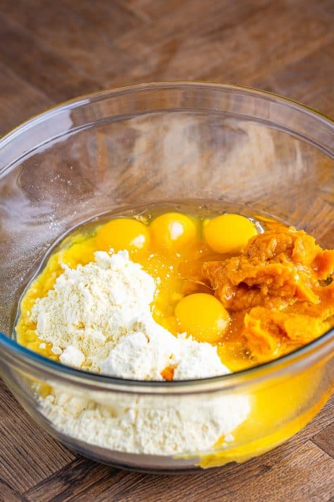 A mixing bowl with cake mix, oil, eggs, and pumpkin puree.