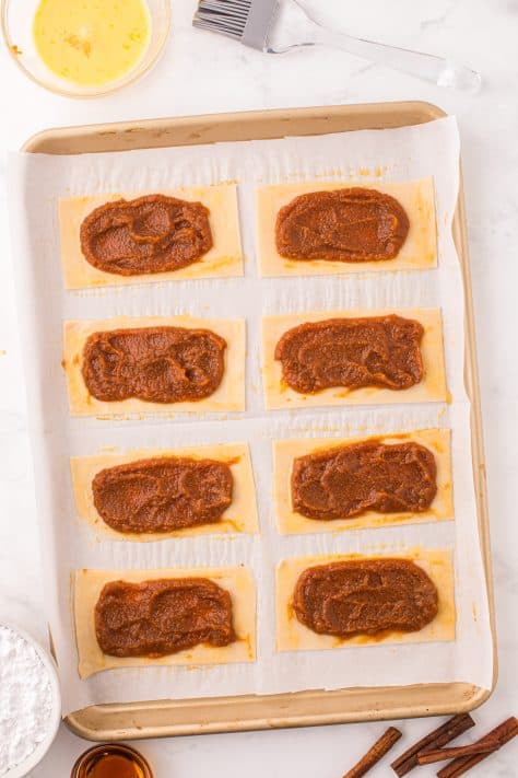 I'm parchment lined baking sheet with refrigerated pie crust cut into rectangles and pop tart pumpkin filling on top.