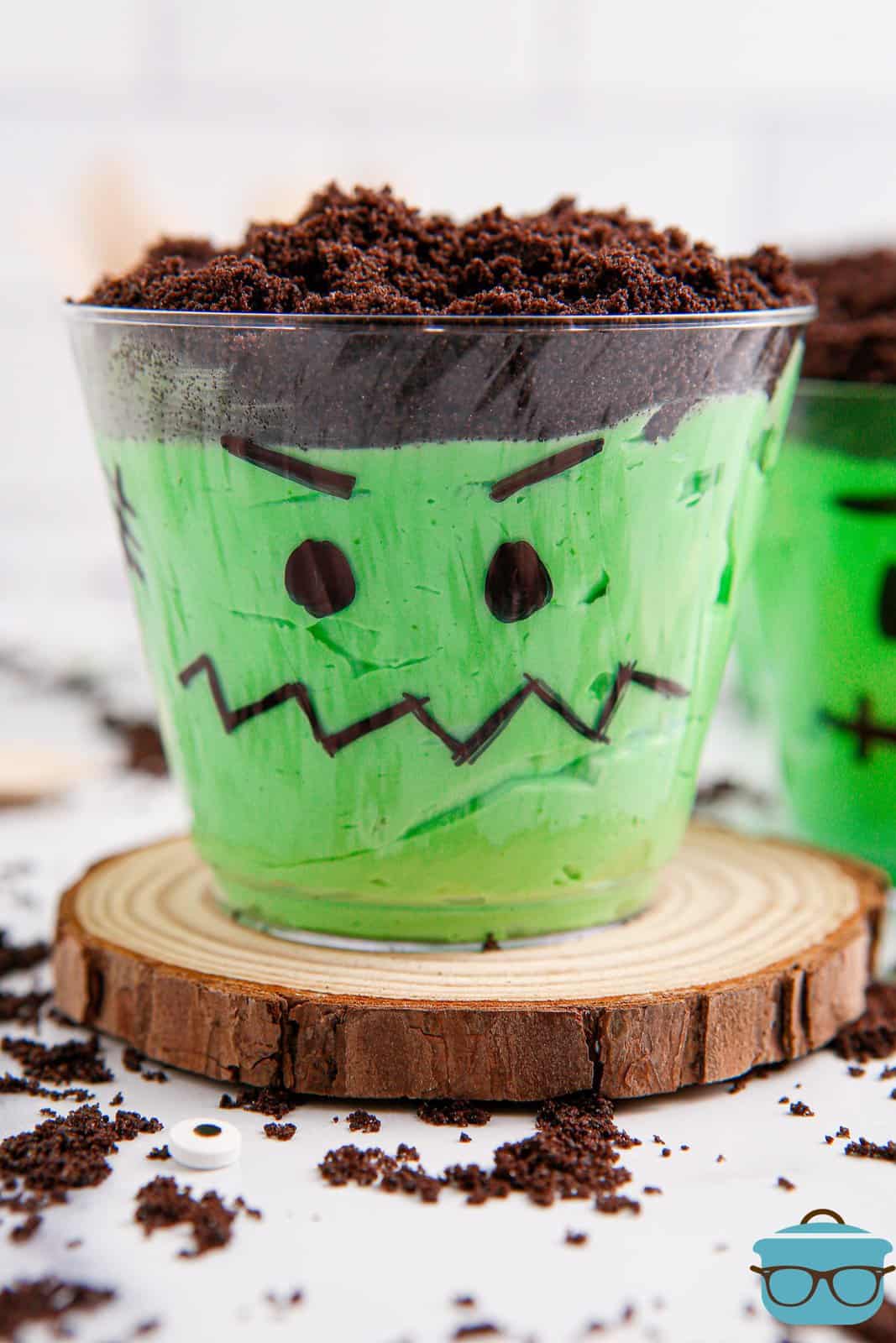A Frankenstein Pudding Cup on a small piece of wood display.