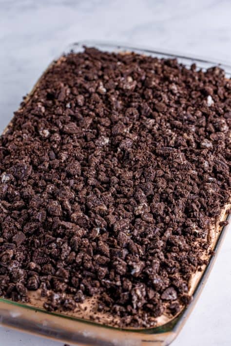 Crushed Oreos on a chocolate frosted chocolate cake.