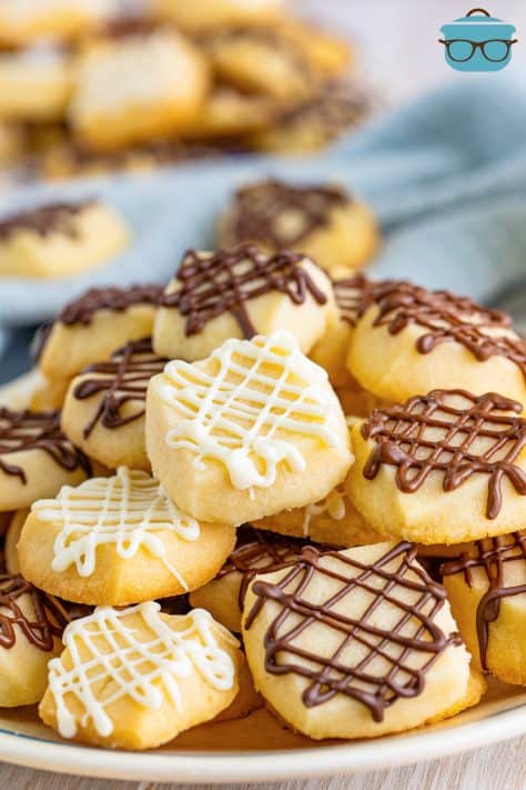 A plate of shortbread cookie bites with chocolate and vanilla drizzle on top.