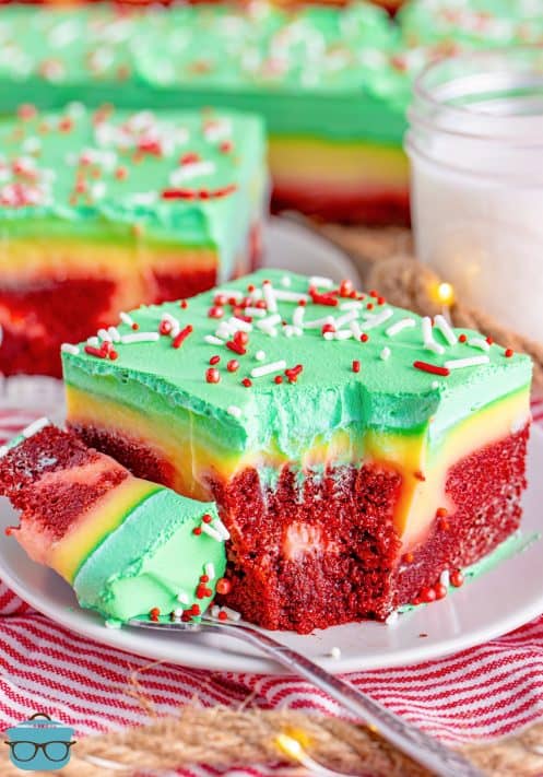 A slice of Christmas Jello Poke Cake with a fork holding a bite on a plate.