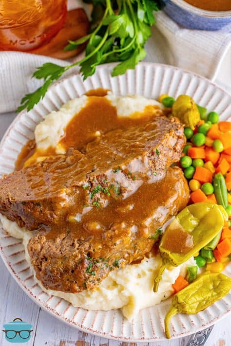 A plate of Mississippi Meatloaf with mashed potatoes, peas and carrots.