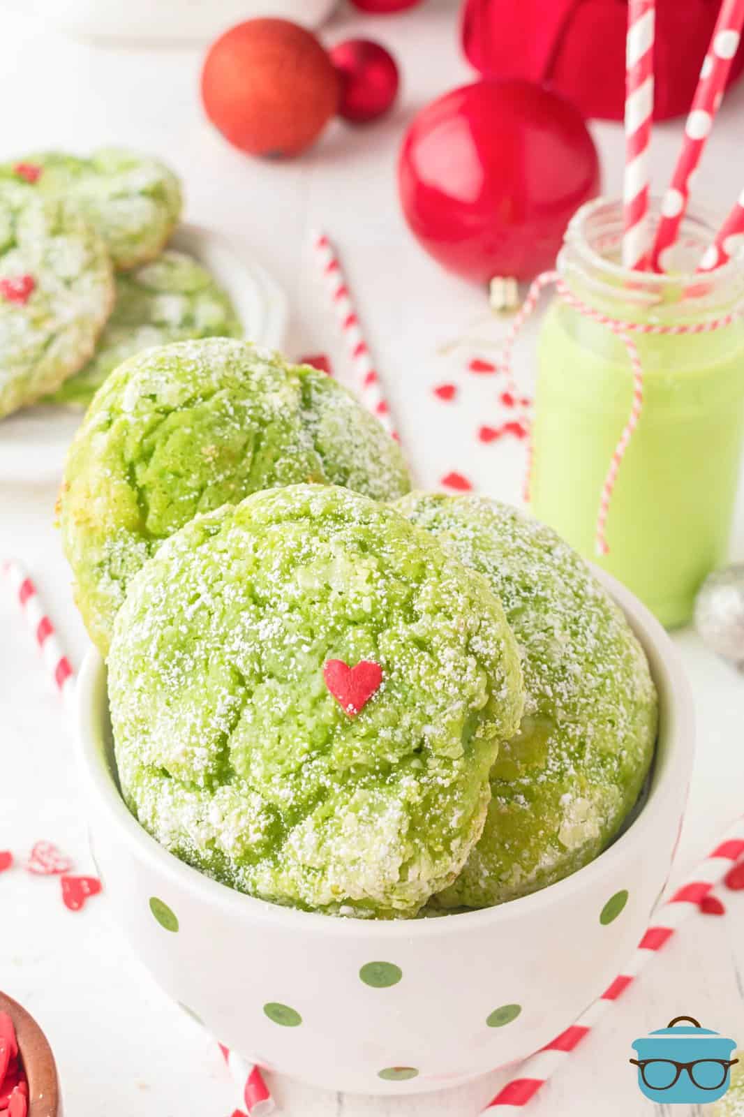 Looking down on a bowl of green cookies with a small, red Grinch heart.