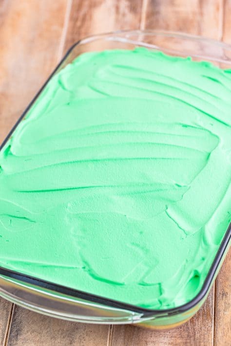 Green whipped topping spread on a cake.