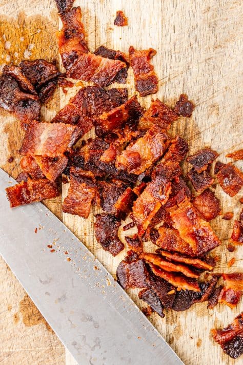 Chopped, cooked bacon on a cutting board.