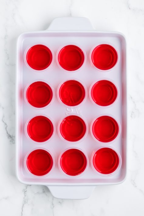Strawberry jello shots on a tray.