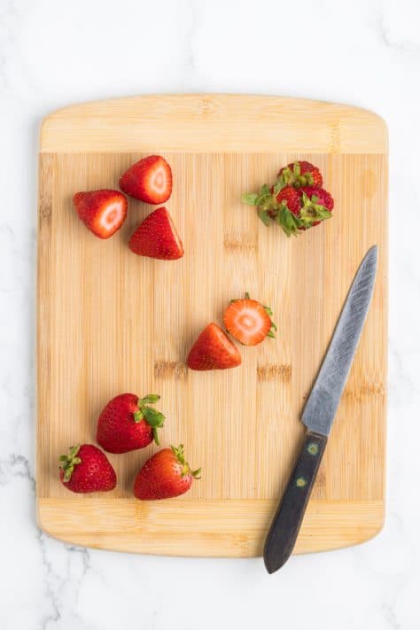 Cut strawberries on a cutting board.