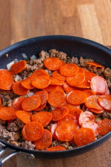 Pepperoni, onion, ground beef and sausage in a skillet.
