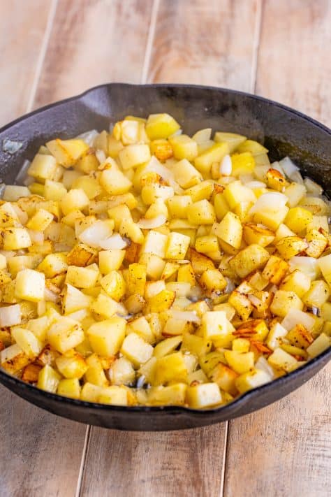 Crispy potatoes cooking in a skillet.
