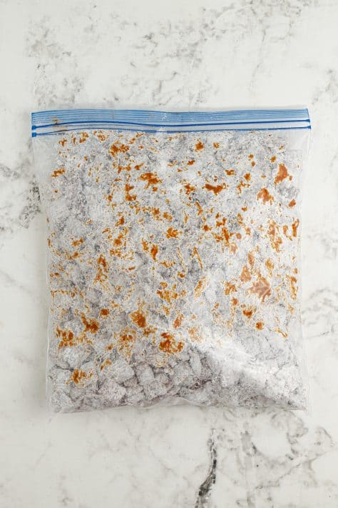 A ziptop bag with powdered sugar and chocolate coated cereal.