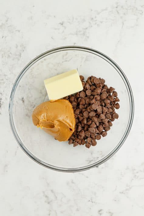 A mixing bowl with chocolate chips, peanut butter, and butter.
