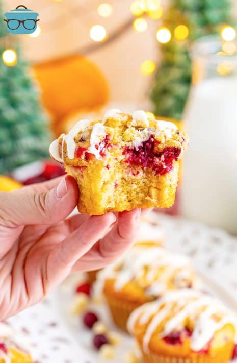 A hand holding a Cranberry Bliss muffin that is missing a bite.