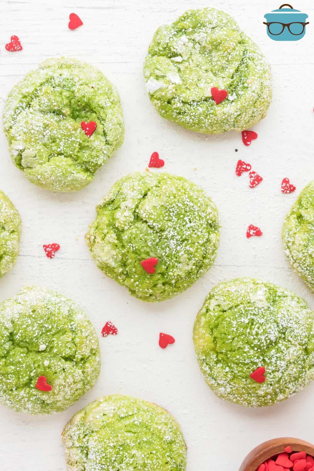A few Grinch Cookies on a baking sheet with red hearts.