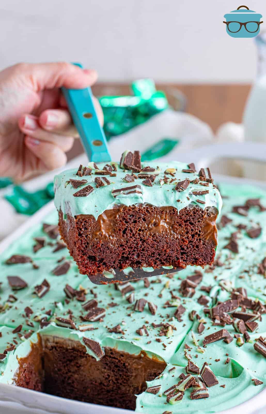 A slice of Mint Chocolate Poke Cake being removed from the pan.
