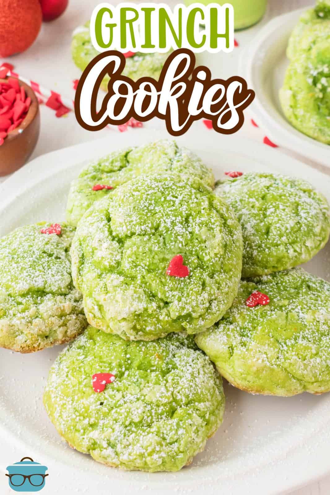 A plate of Green Grinch Cookies with hearts and powdered sugar.