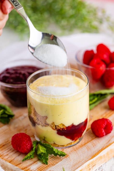 Layered creme brulee trifle with a spoon pouring sugar on top.