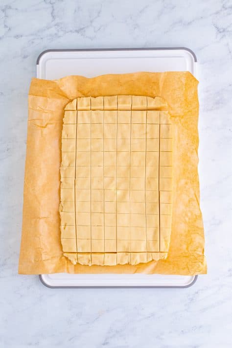 Cookie dough cut into squares on a sheet.