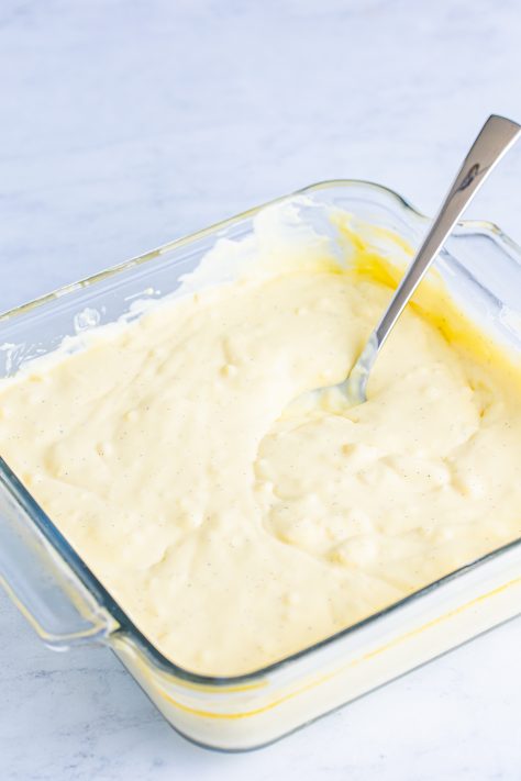 A spoon in a baking dish after mixing up the custard.