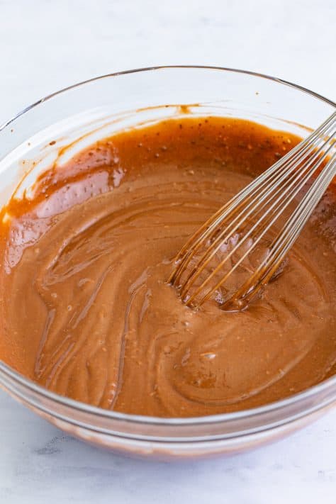 A mixing bowl with chocolate pudding and a whisk.