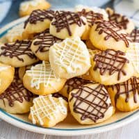 Close up looking at a plate of chocolate drizzled shortbread cookies.