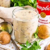 A jar of Cream of Mushroom soup with a few ingredients around it.