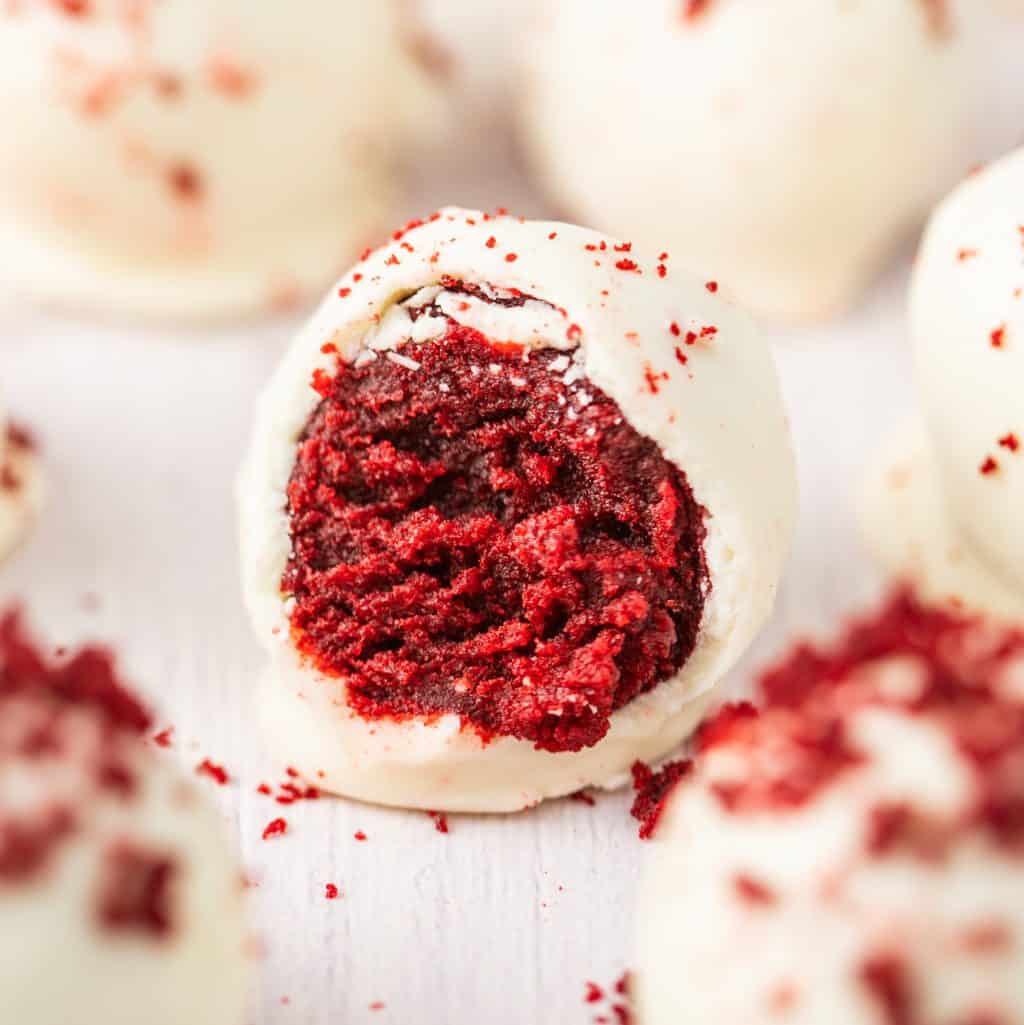 A Red Velvet cake ball with a bite taken out.