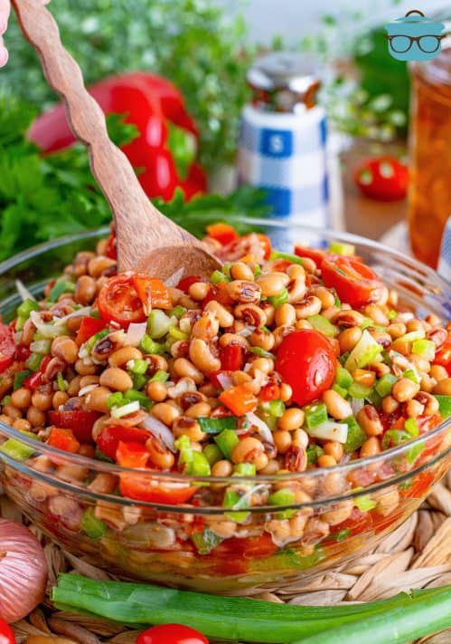 A wooden spoon in a bowl of Black Eyed Pea Salad.