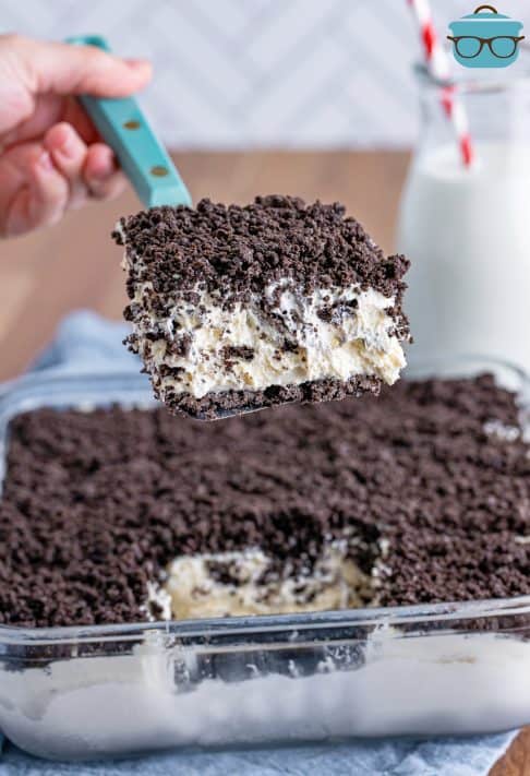 A serving utensil holding a slice of No Bake Oreo Dessert above the rest of the treat.
