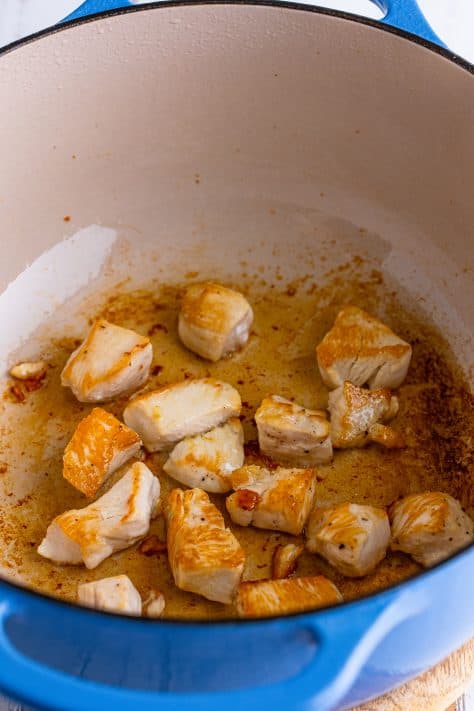 Cooked diced chicken in a dutch oven.