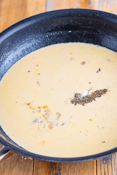 Salt, pepper, Worcestershire sauce in a creamy sauce in a skillet.