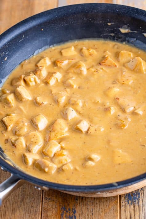 Chicken added to a creamy sauce in a skillet.