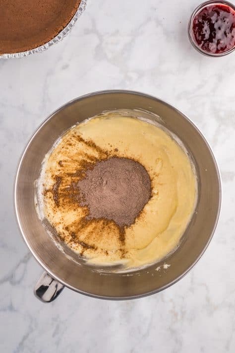 Chocolate pudding mix being added to cheesecake mixture in a bowl.
