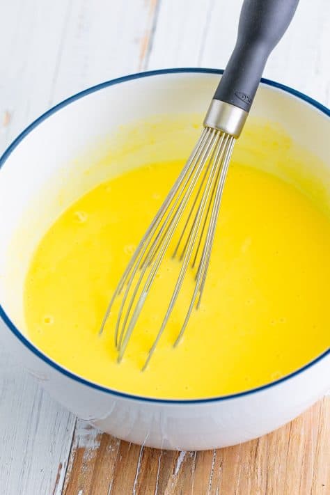 Vanilla pudding in a mixing bowl with a whisk.