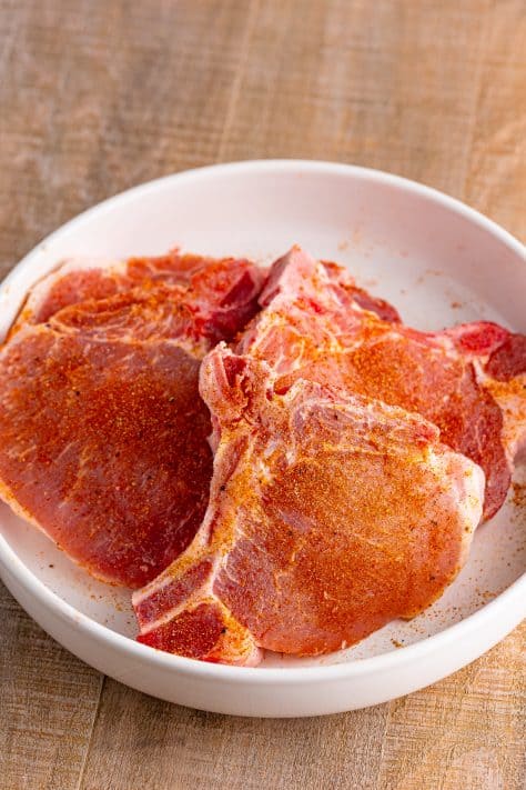 Seasoned pork chops in a bowl.
