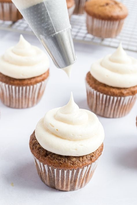 piping frosting onto gingerbread cupcakes.