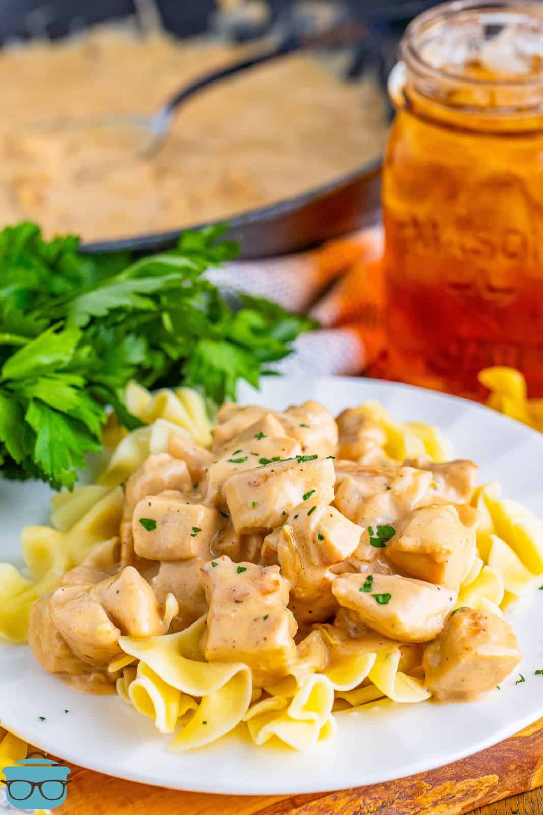 A plate of Chicken Stroganoff with creamy sauce next to a glass of tea