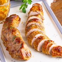 A sliced Slow Cooker Pork Tenderloin sliced up on a baking sheet with parchment paper.