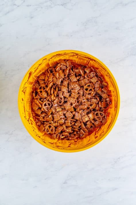 A bowl of Chex mix and other mixes covered in chocolate mixture.