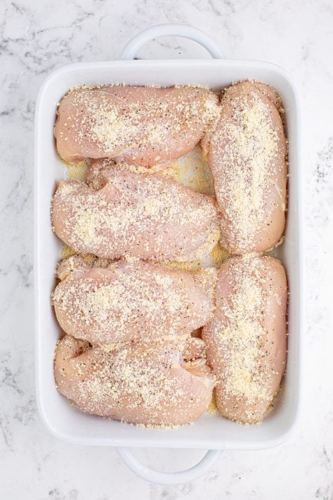 A baking dish with grated parmesan, salt and pepper.