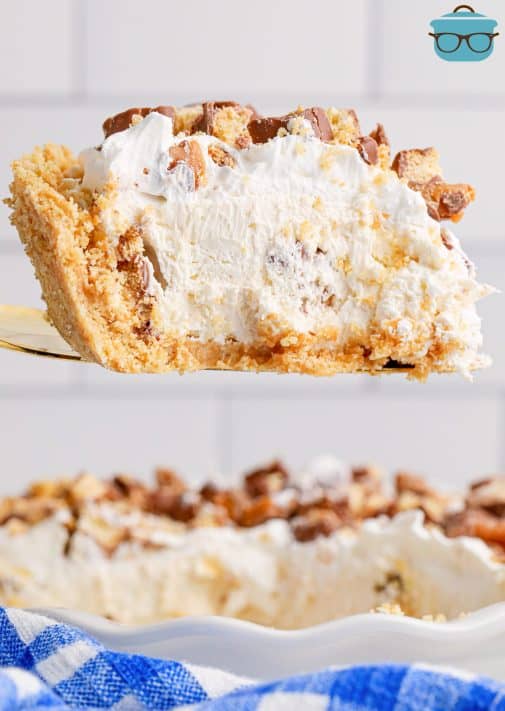 A slice of No Bake Twix Pie being held above the rest of the pie.