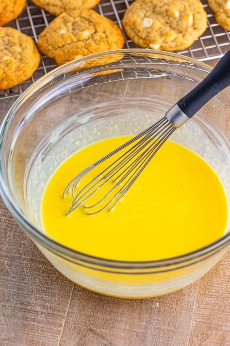 A mixing bowl with vanilla pudding and a whisk.