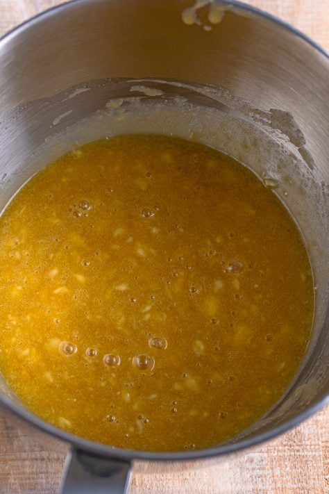 A mixing bowl with butter, brown sugar, sugar, bananas, egg, and vanilla.