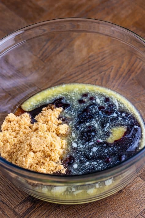 A mixing bowl with blueberry pie filling, brown sugar, melted butter, and vanilla.