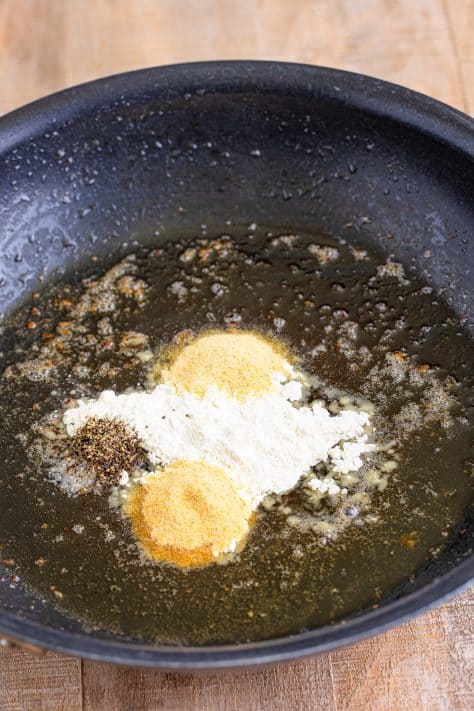 A skillet with melted butter, flour, garlic powder, onion powder, pepper, and salt.