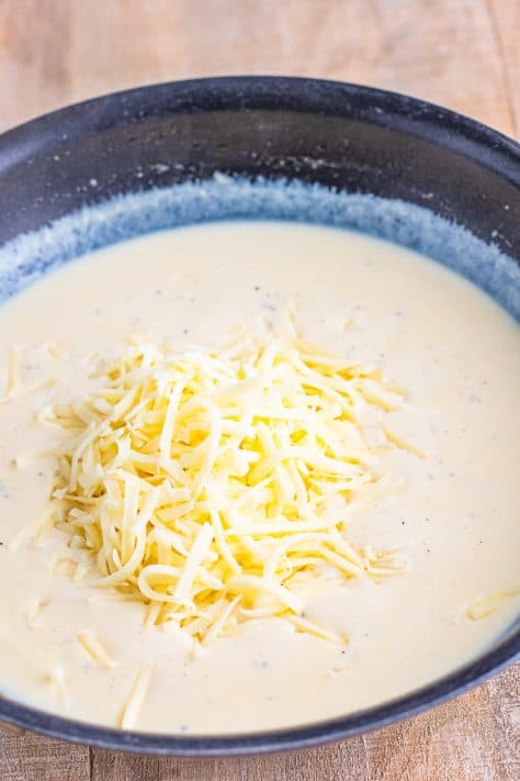 Mozzarella cheese on top of a creamy sauce in a skillet.